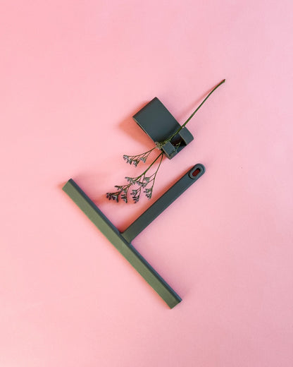 Von oben fotografierter grauer Silikon-Duschabzieher mit Haken und dekorativer Blume.