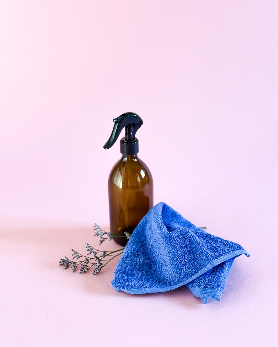 500ml Glas-Sprühflasche in Braun kombiniert mit einem blauen Baumwoll-Reinigungstuch und Blume.